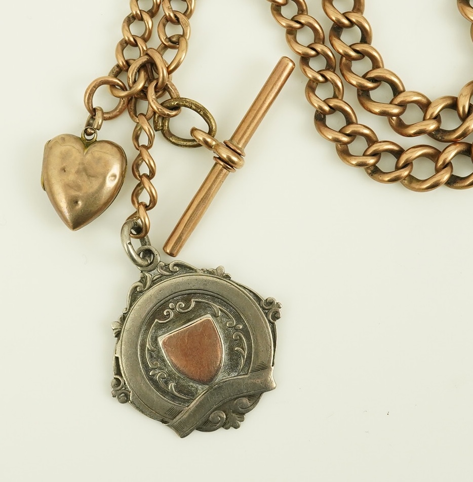 An early 20th century 9ct gold graduated curb link albert, hung with a silver medallion and a heart shaped charm